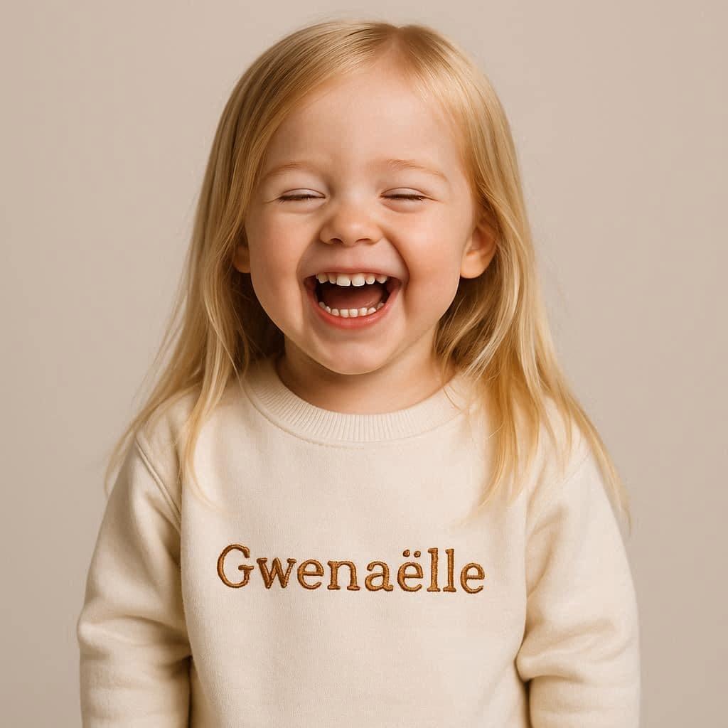 Petite fille qui rigole elle porte un pull avec ecrit gwenaelle