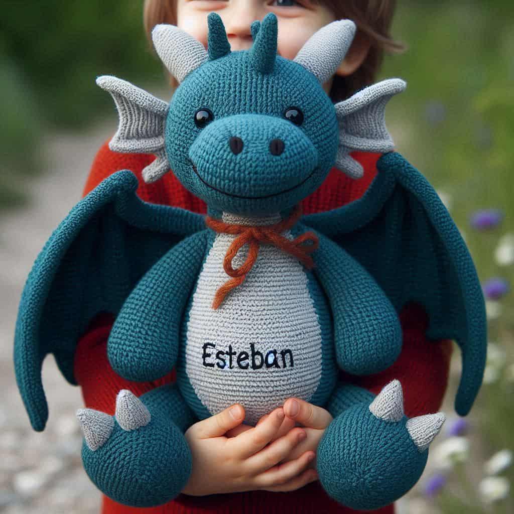 Une peluche dragon en tricotin avec le prenom esteban dans les bras d un petit garcon